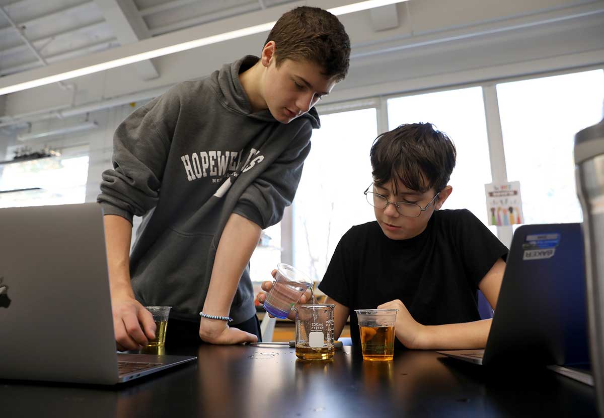 Two boys with lab equipment and a laptop in science class
