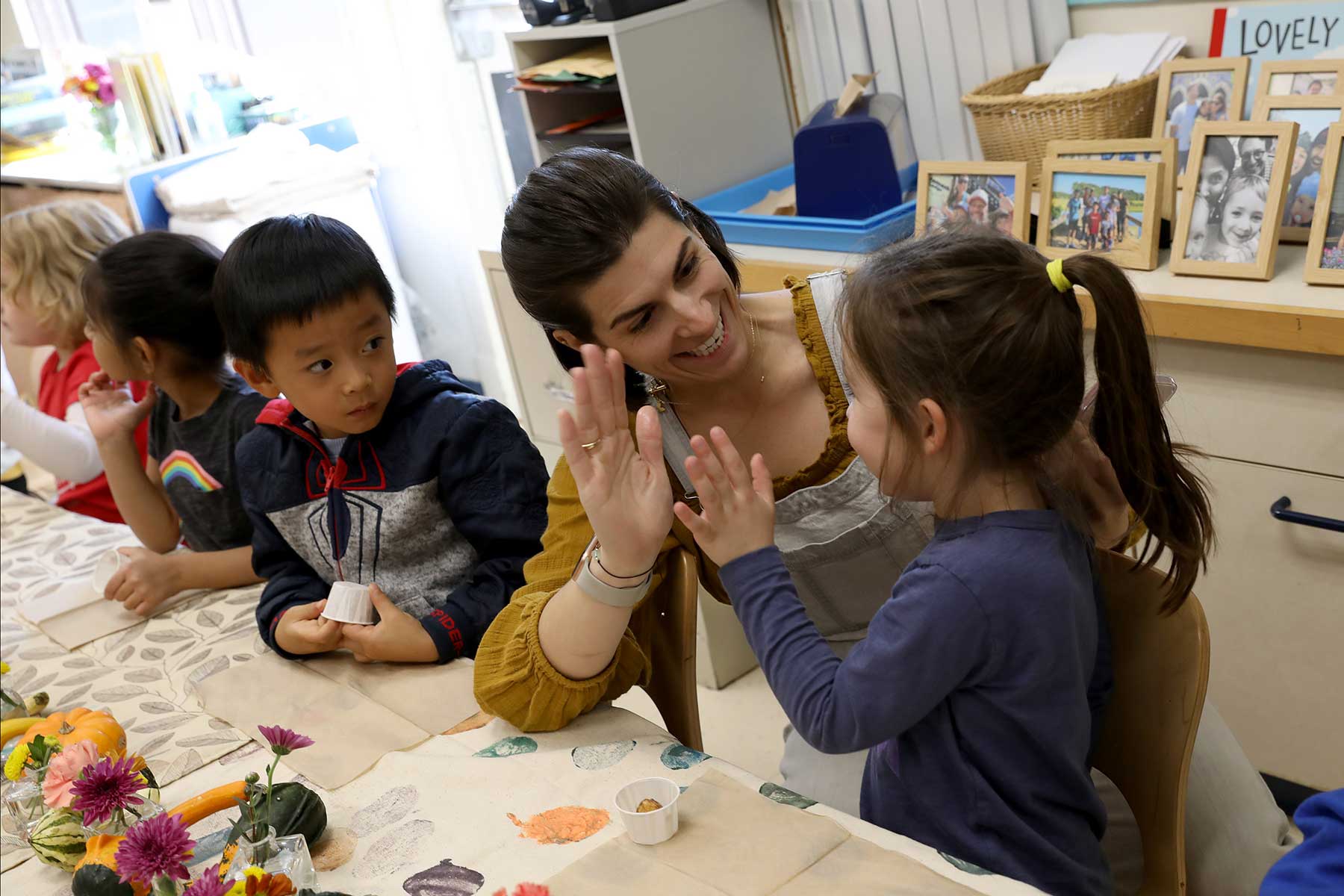 A teacher gives a pre-k student a high five