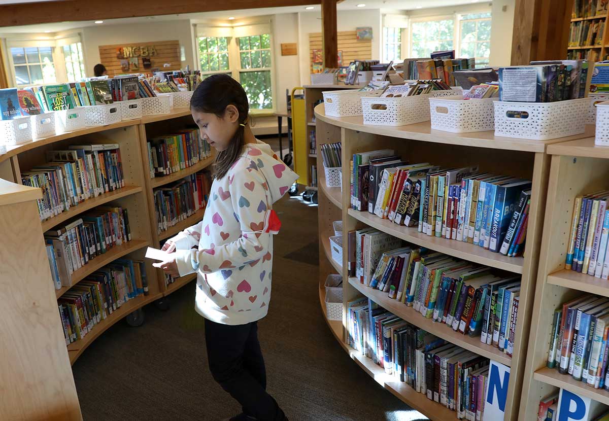 A girl stands in the library stacks to select a book