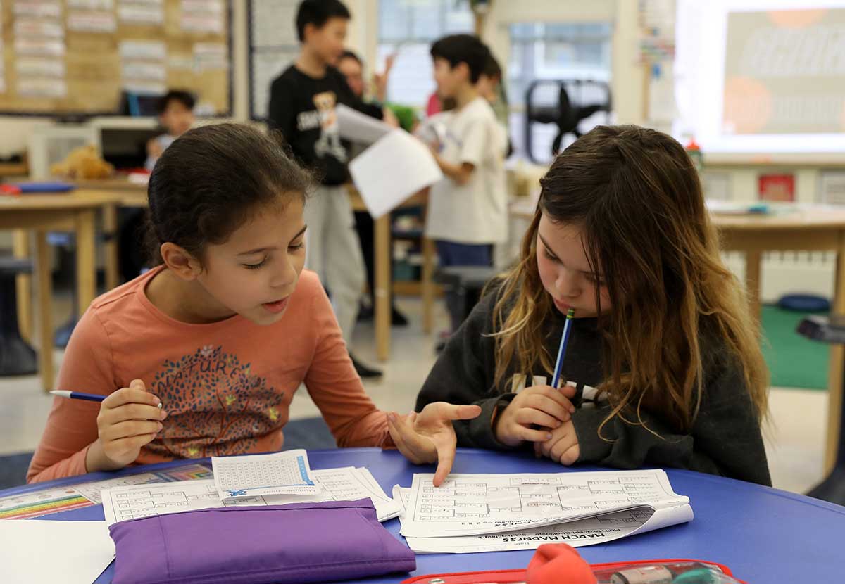 Two students sit together and work on a math problem